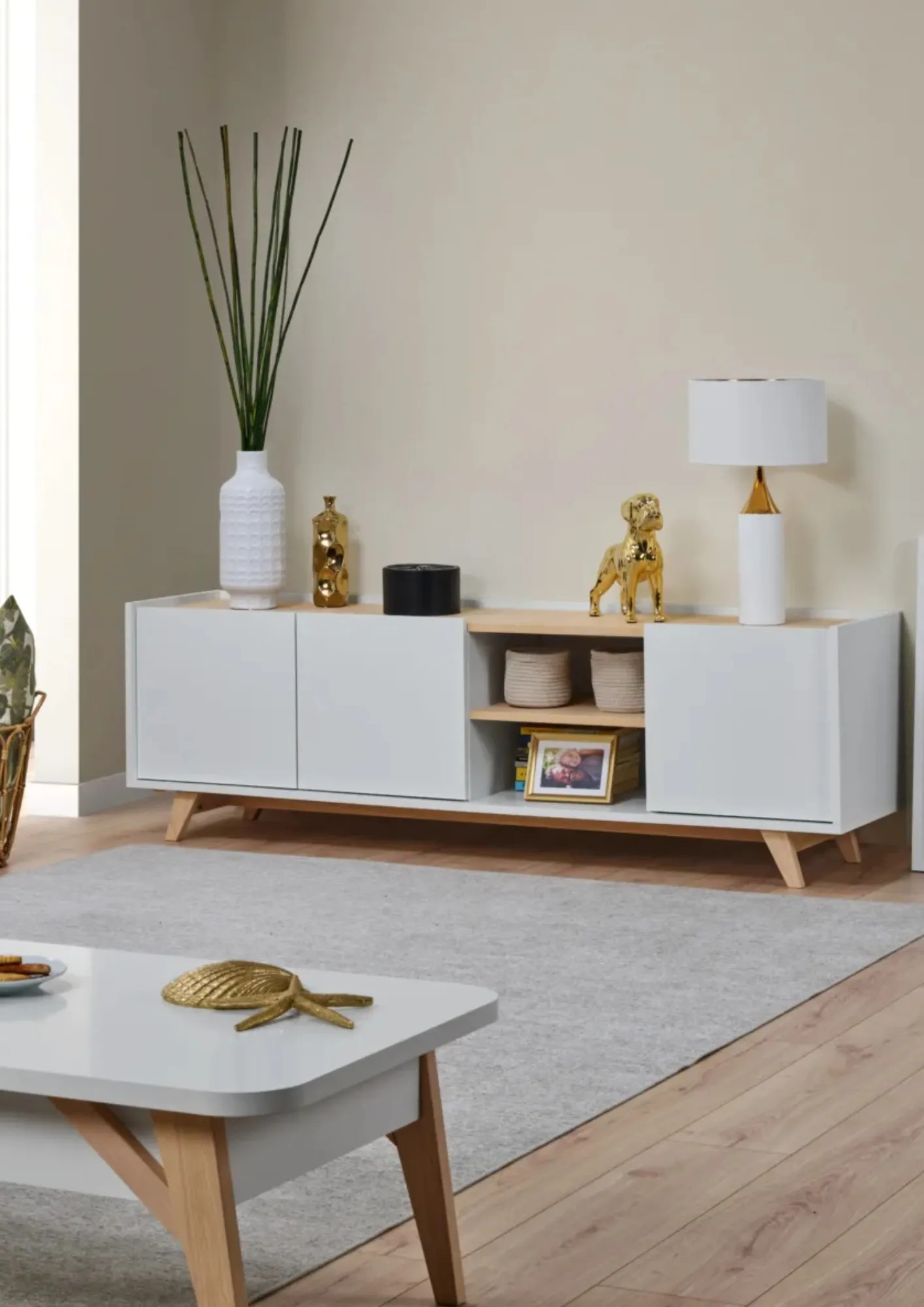 Móvel de TV e mesa de centro brancos com pés de madeira numa sala de estar